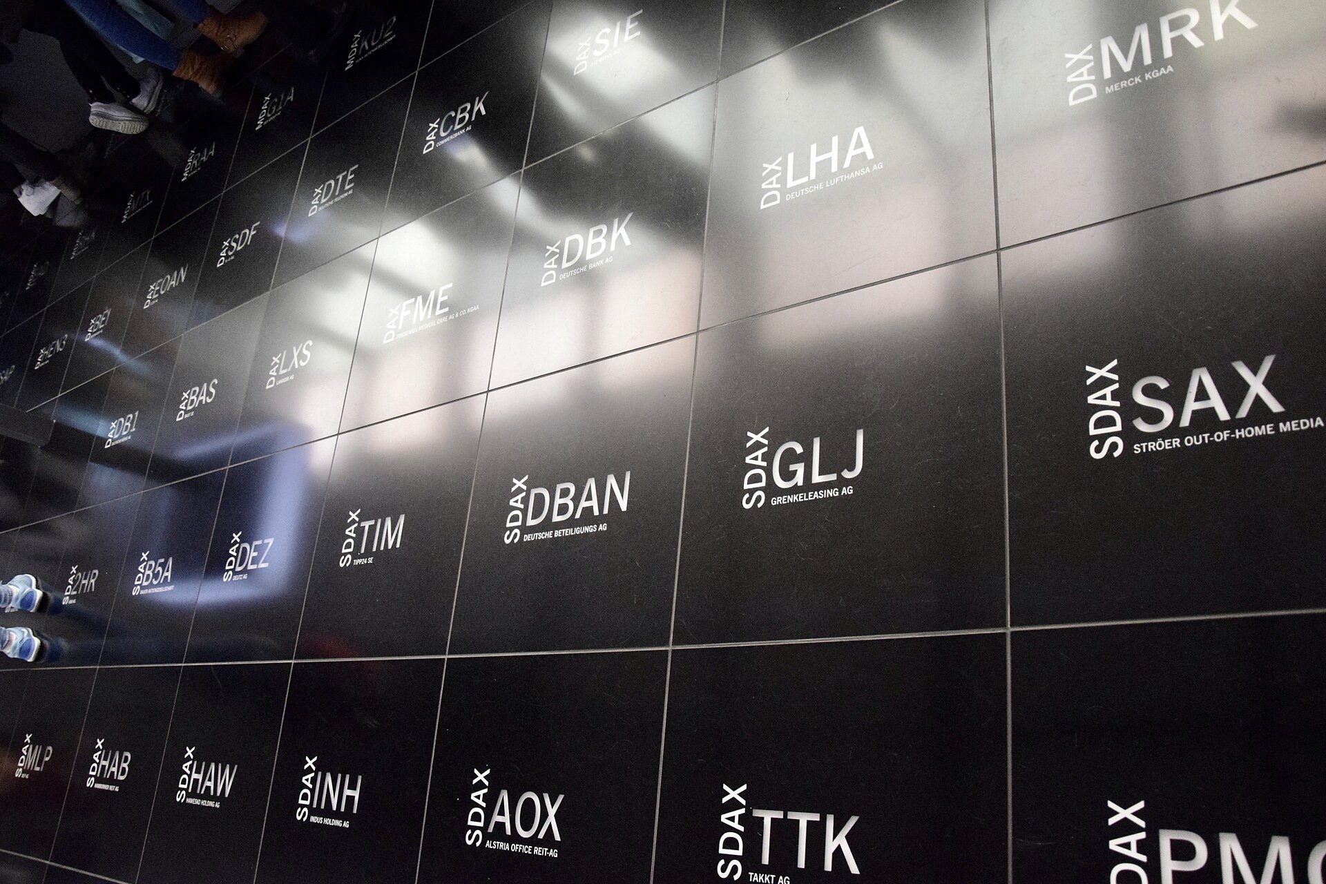 A stock exchange trading floor with a red, falling index chart on an overhead display