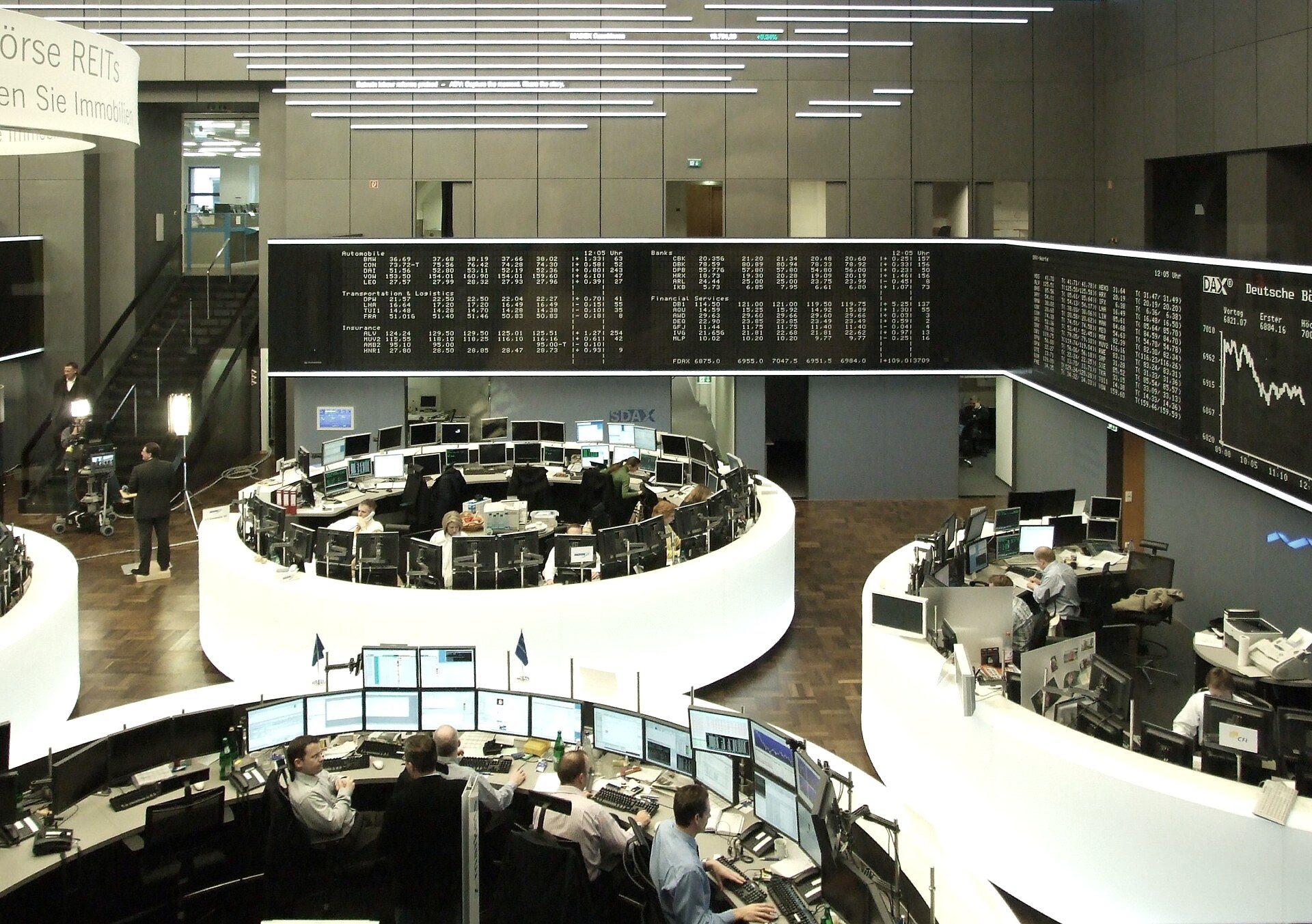 A stock exchange trading floor with a volatile index chart reversing direction on an overhead display