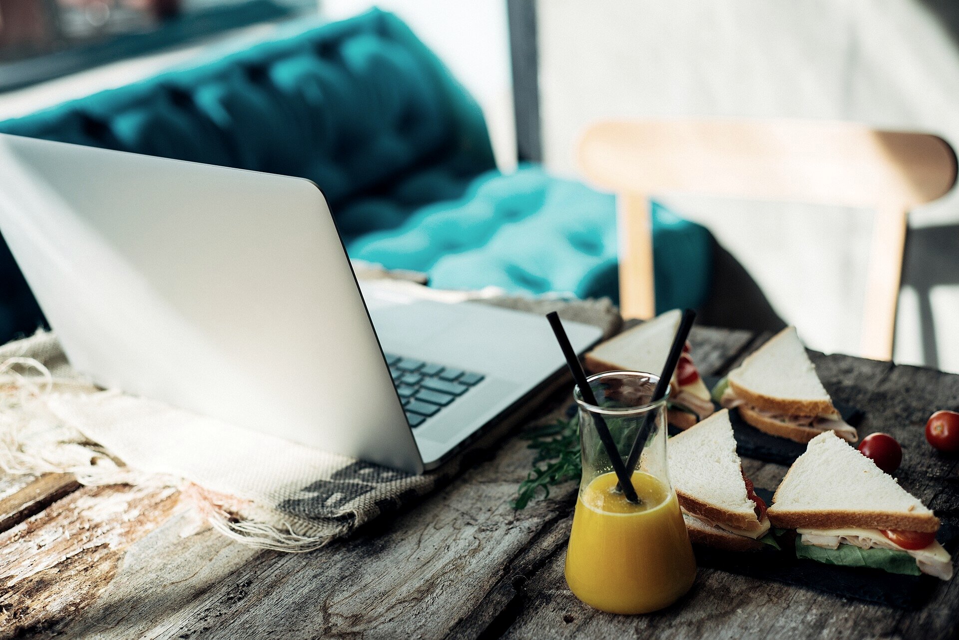 A laptop and a Thai baht note on a beachfront cafe table in Koh Phangan, with a passport and a cup of coffee beside a slow-turning ceiling fan