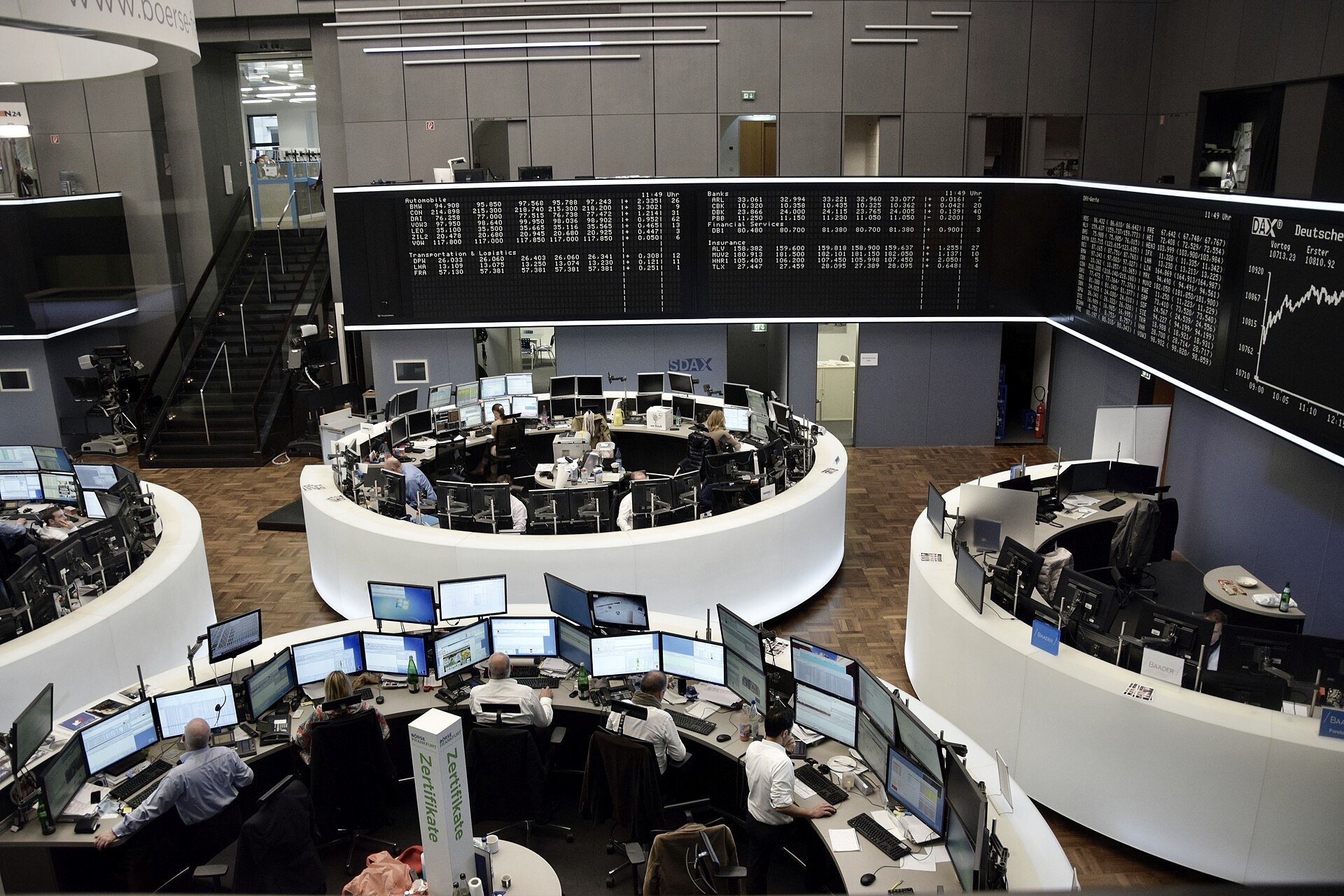 A New York trading floor screen tracking a record stock index level beside a chart of the VIX volatility gauge easing to multi-month lows